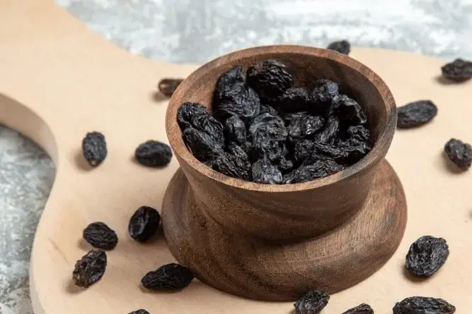 Close-up of raisins and dry grapes on wooden table