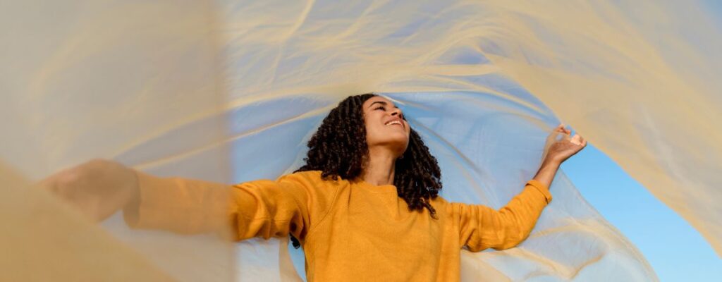 Woman smiling while tapping on hand, symbolizing EFT healing