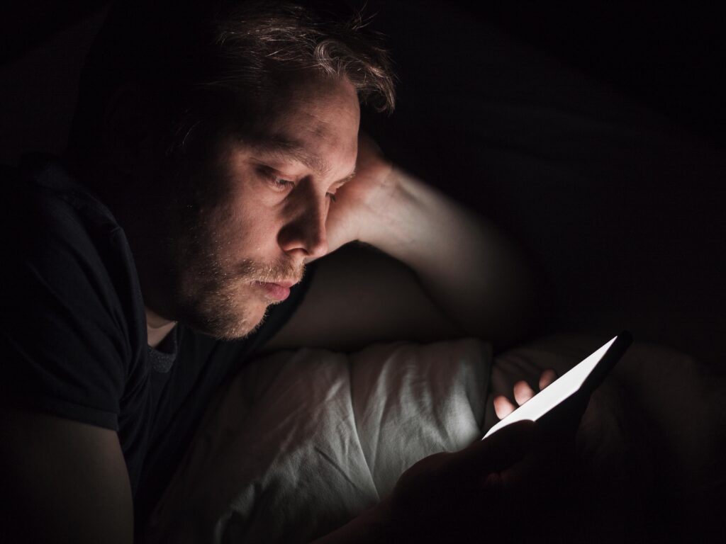 Stressed man reading bad news on phone illustrating doomscrolling