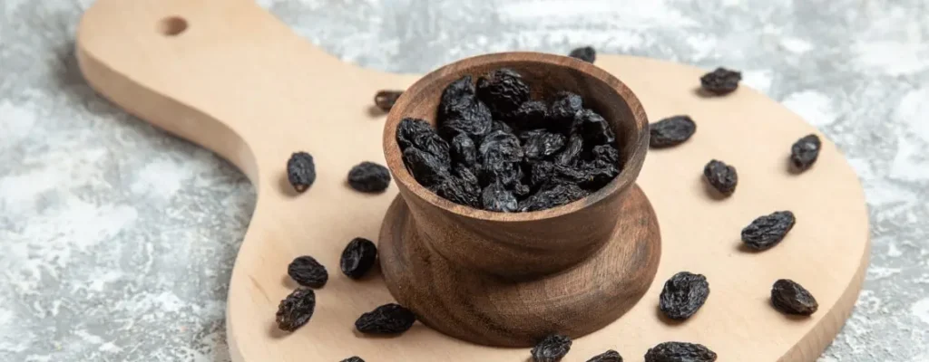 Close-up of raisins and dry grapes on wooden table|black-raisins-benefits|black-raisins-benefits|black-raisins-benefits|black-raisins-benefits||||