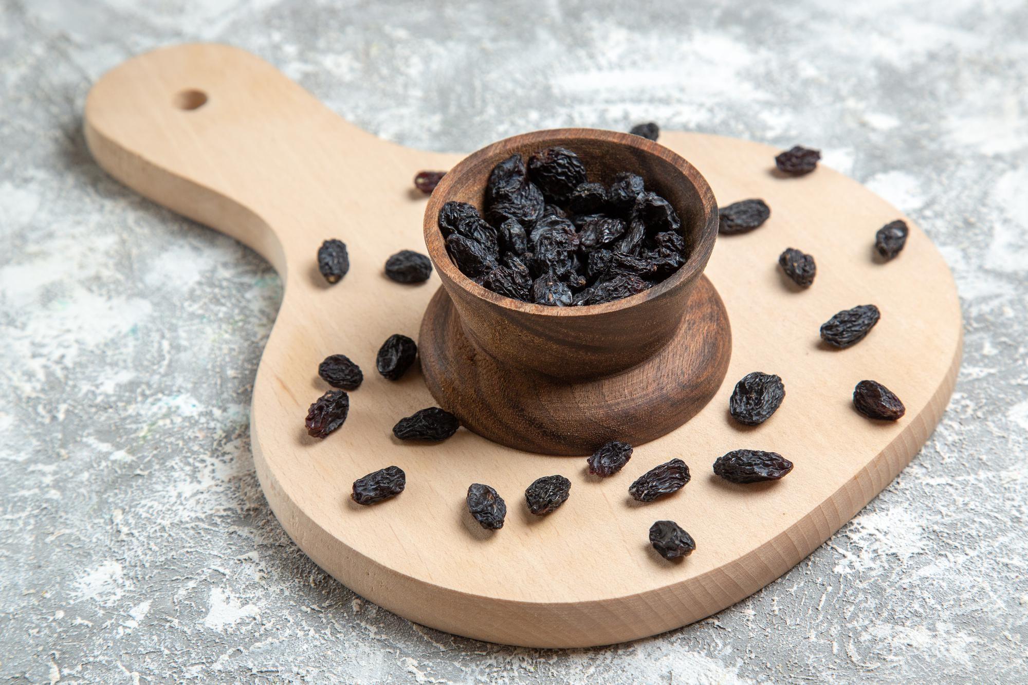 Close-up of raisins and dry grapes on wooden table