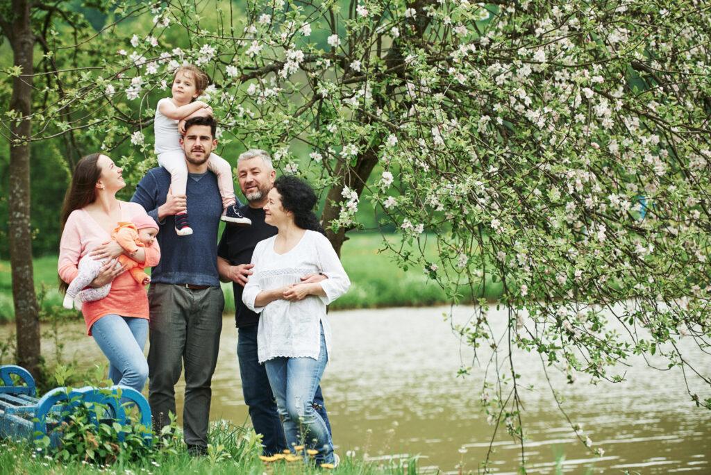 Near the bench and lake. Family photo. Full length portrait of cheerful people standing outdoors together.